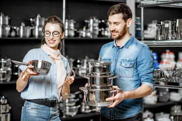 Couple choosing pans for cooking in the shop