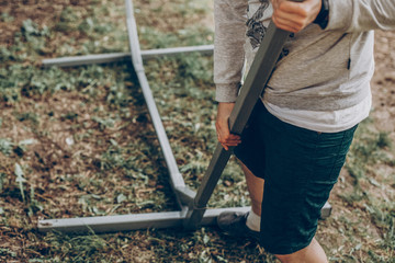 Strong handsome man constructing hammock support bars, father putting together hammock for camping trip, how to do it yourself concept