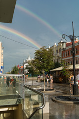 Two rainbows in the blue sky after a rain against the background of city to the avenue.