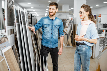 Beautiful young couple choosing ceramic tiles for their house repairment in the building shop