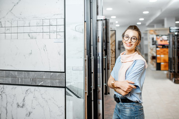 Portrait of a young woman designer choosing ceramic tiles for the house repairment in the building shop