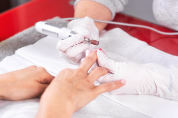 Professional manicure process, cleaning the nails with a manicure milling cutter, at beutician salon .