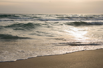 Scenic view of the waves of the blue sea on the sandy shore.
Wild nature. Storm. Sunset on the sea.