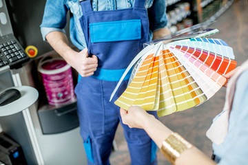 Choosing paint from color swatches in the building shop, close-up view