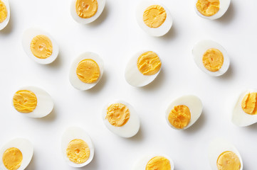 Boiled eggs pattern on a white background viewed from above. Top view. Egg half. Yolk - obrazy, fototapety, plakaty