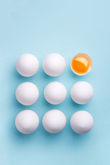 White eggs pattern (broken and whole) on a blue background viewed from above. Top view. Copy space