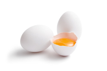 White eggs, whole and broken egg half with a yolk isolated on a white background.