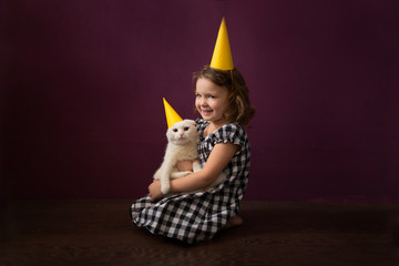 Festive kid holding white cat yellow holiday cap