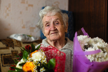 Portrait of old woman with a bouquet of flowers.
