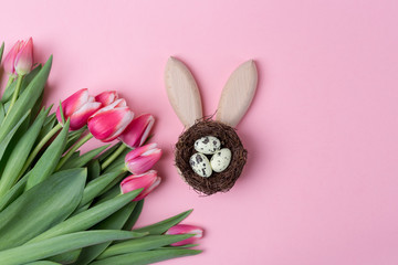 Happy Easter holiday background with small nest with eggs and pink flowers tulip. Flat lay. Copy space. Space for text.