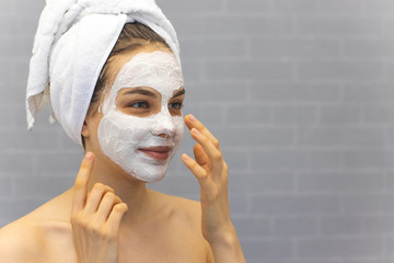 Attractive Young Woman Wrapped with Bath Towels and cream mask on the face	