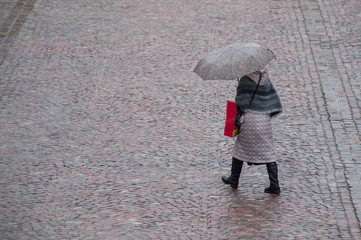 portrait of woman with grey umbrella on cobbles place in the city