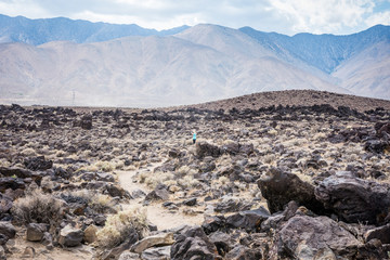 Young woman photographer explores Fossil Falls in California. Photo shows the scale of the area