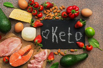 Keto diet food. Healthy low carbs products.Keto diet concept. Vegetables, fish, meat, nuts, seeds, strawberries, cheese on a brown background. Top view. Signboard. - obrazy, fototapety, plakaty