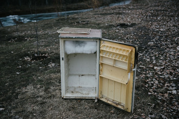 An old open refrigerator stands outside on the street