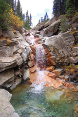 Clear mountain water cascades over colorful mineral stained river stones make abstract waterfall in South mineral creek river stones along the Rico Silverton trail in the San Juan range of the Colorad