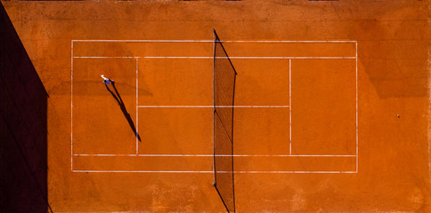 Aerial view of a tennis court with a player who is training after work.