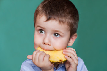 Cute little boy eating pineapple. Close-up Portrait