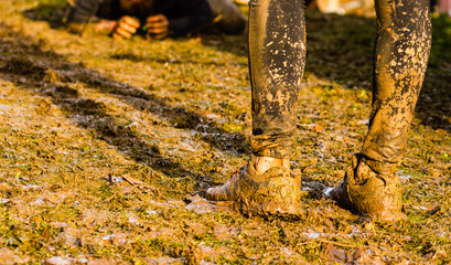 Mud race runners passing under a barbed wire obstacles during extreme obstacle race,detail of legs