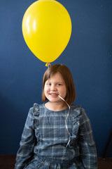Fototapeta na wymiar funny girl with yellow balloon on blue background