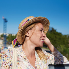 Young beautiful smiling European girl is sitting in a Ferris wheel in a Luna park. She is observing a city from bird’s eye view.