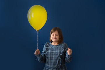 Fototapeta na wymiar funny girl with yellow balloon on blue background