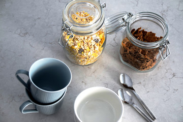 Breakfast ready with mugs, bowls, and jars filled with cereals
