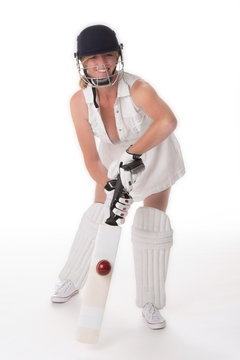 Woman cricketer in a white revealing dress with a safety helmet, shin pads, a bat and ball.