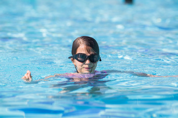 a little girl in a black swimming mask in the pool whith body under the water