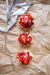 Beautiful cupcakes with strawberries along with a branch on kraft paper