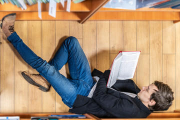 top view of student lay on wooden floor and read a book b