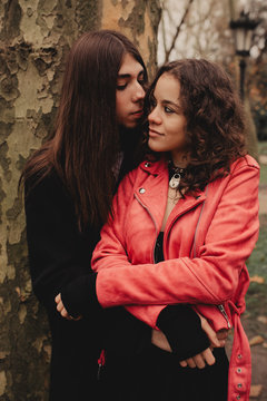 Long haired man hugging and kissing woman near tree