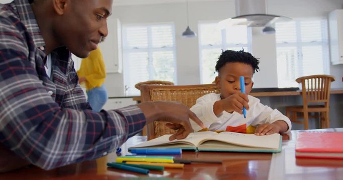 Side view of black father helping his son with homework at comfortable home 4k