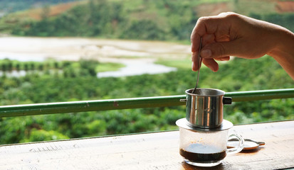 Brewing coffee luwak in the morning in nature. View of the coffee plantation. Man's hand with a spoon and coffee kettle