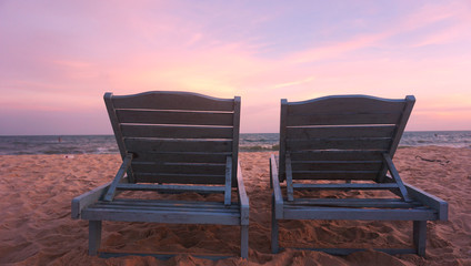 Two chairs (sun beds) stand on the beach at sunset. Romantic trip to Vietnam or Tropical island
