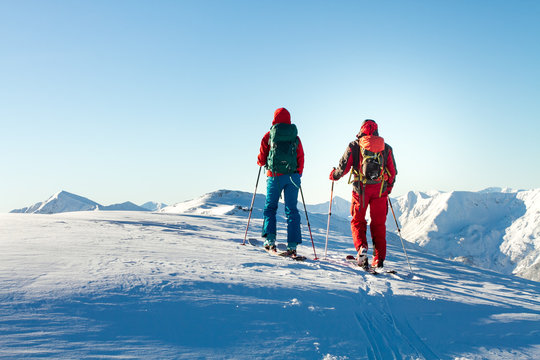 Man and woman ski tourer enjoying the view on a summit in the alps.