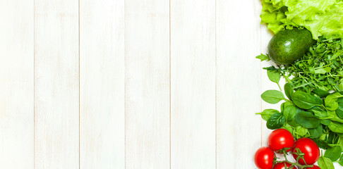 Fresh green spinach leaves, arugula rucola, avocado, cherry tomatoes and lettuce leaves on white wooden rustic background top view copy space. Ingredient for salad, healthy food diet Nutrition concept