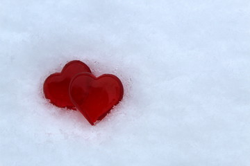 two red plastic hearts are on white snow