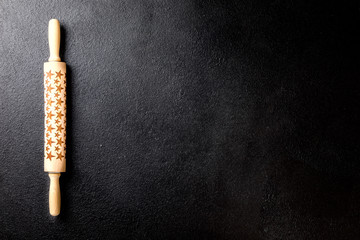 Rolling pin with a pattern in the form of stars on a black board. Baking Background .Preparation for cooking Food. Concept for Menu, Recipe, Ingredient. Copy space for Text.