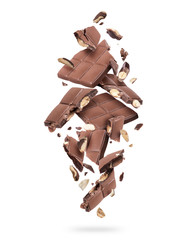 Pieces of chocolate bar with nuts falling down on white background
