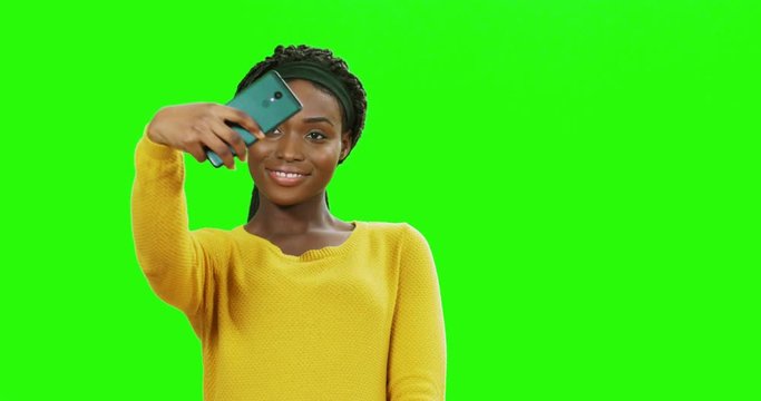 Attractive smiled young African American woman taking selfie photos on the smartphone camera and posing on the alpha channel background. Chroma key.