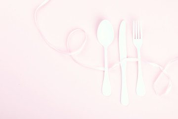 Festive table setting with fork, knife and hearts  on pink pastel background.Romantic dinner. Space for text. Top view.