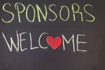 sponsors welcome concept on blackboard with small wooden red heart