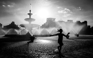 Naklejka na ściany i meble Silhouette of young girls playing in the city centre fountain in Bucharest , Unirii square 