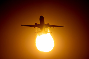 Silhouette of airplane in sunset landing on airport
