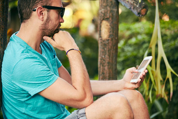 Modern man using cellphone outdoors.