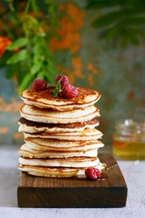 A stack of lush punkcakes for breakfast on a gray background. High pile of delicious pancakes with berries.American Cuisine, Copy space