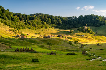 Naklejka premium Transylvania landscape with old wood house and haystack in the misty morning in Romania 