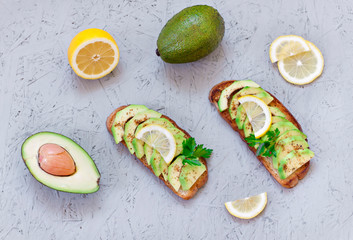 The concept of proper nutrition. Vegetarian menu. Toasts with avocado, lemon, chilli or paprika on a gray background