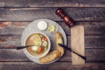 Diet sorrel soup with quail eggs, tomatoes, croutons and sour cream. Served by cutlery and pepper mill on a wooden table